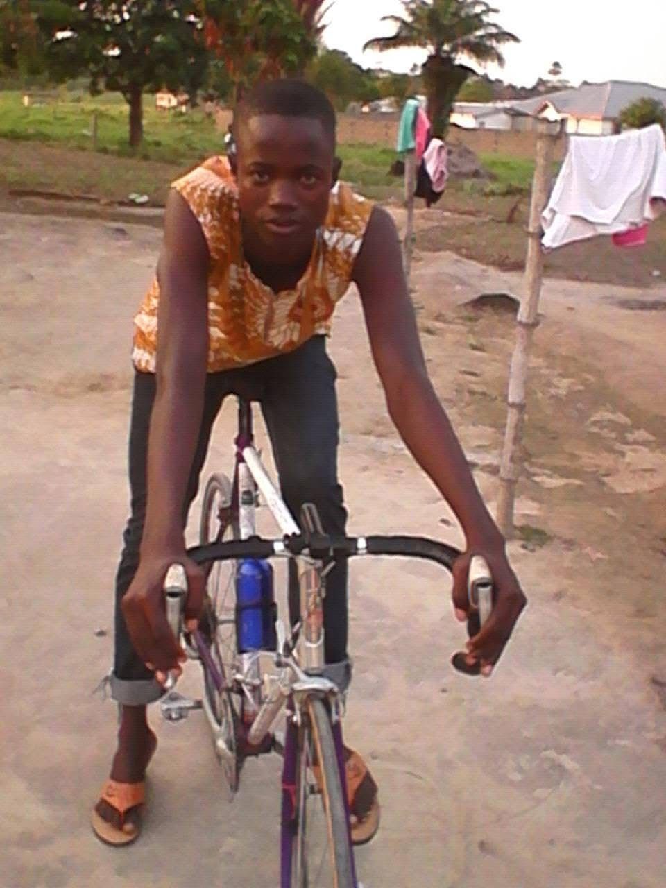 A young Ibrahim Jalloh on his first bicycle on a dirt road in Lunsar